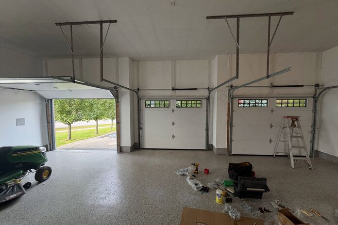 Technician installing new garage doors inside a three-car garage