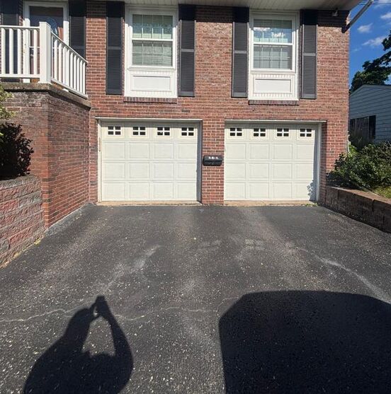 Two single raised-panel garage doors on a brick home