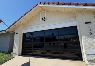 Black full-view glass garage door on a stucco house