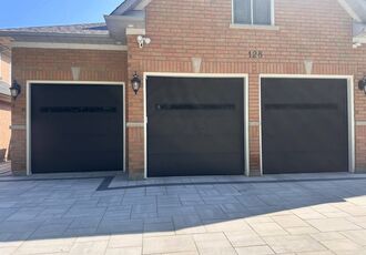 Three black flush garage doors on a brick home